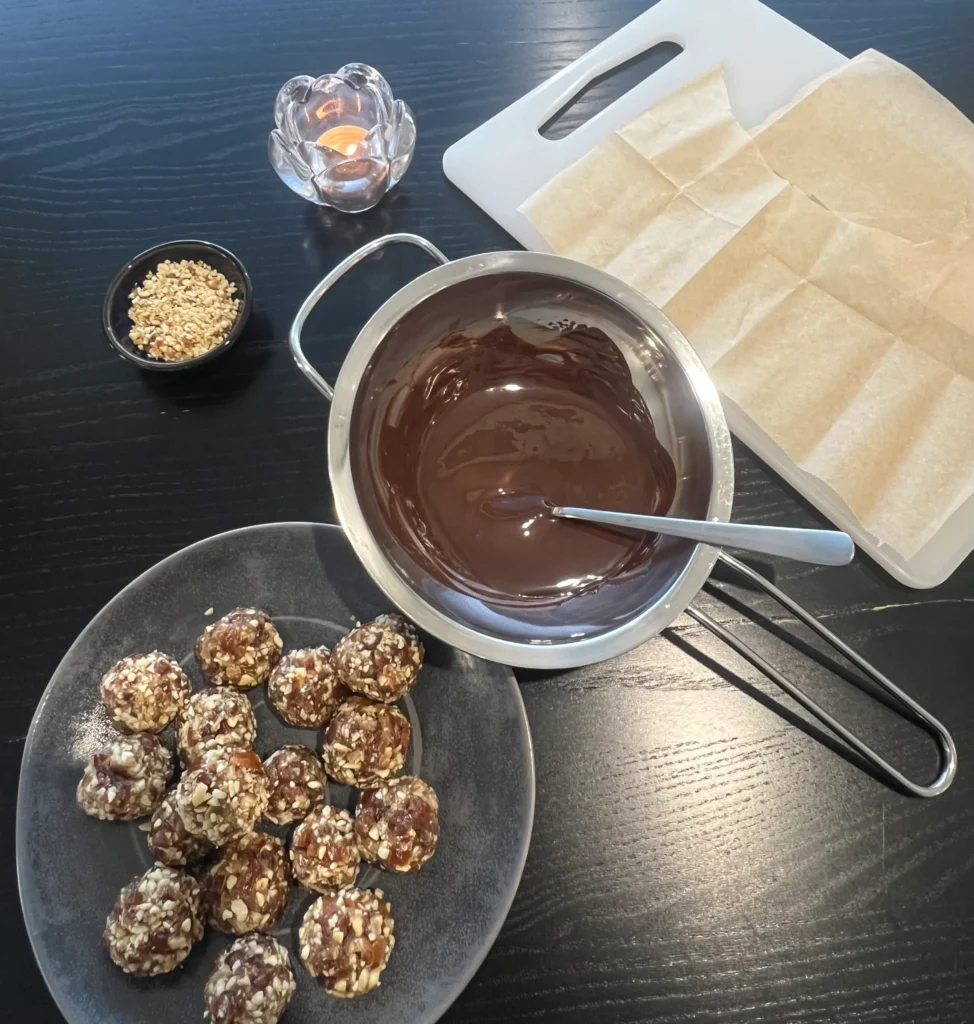 Date and cashew nut balls, melted chocolate to dip them in and crumbled nuts for garnishing.