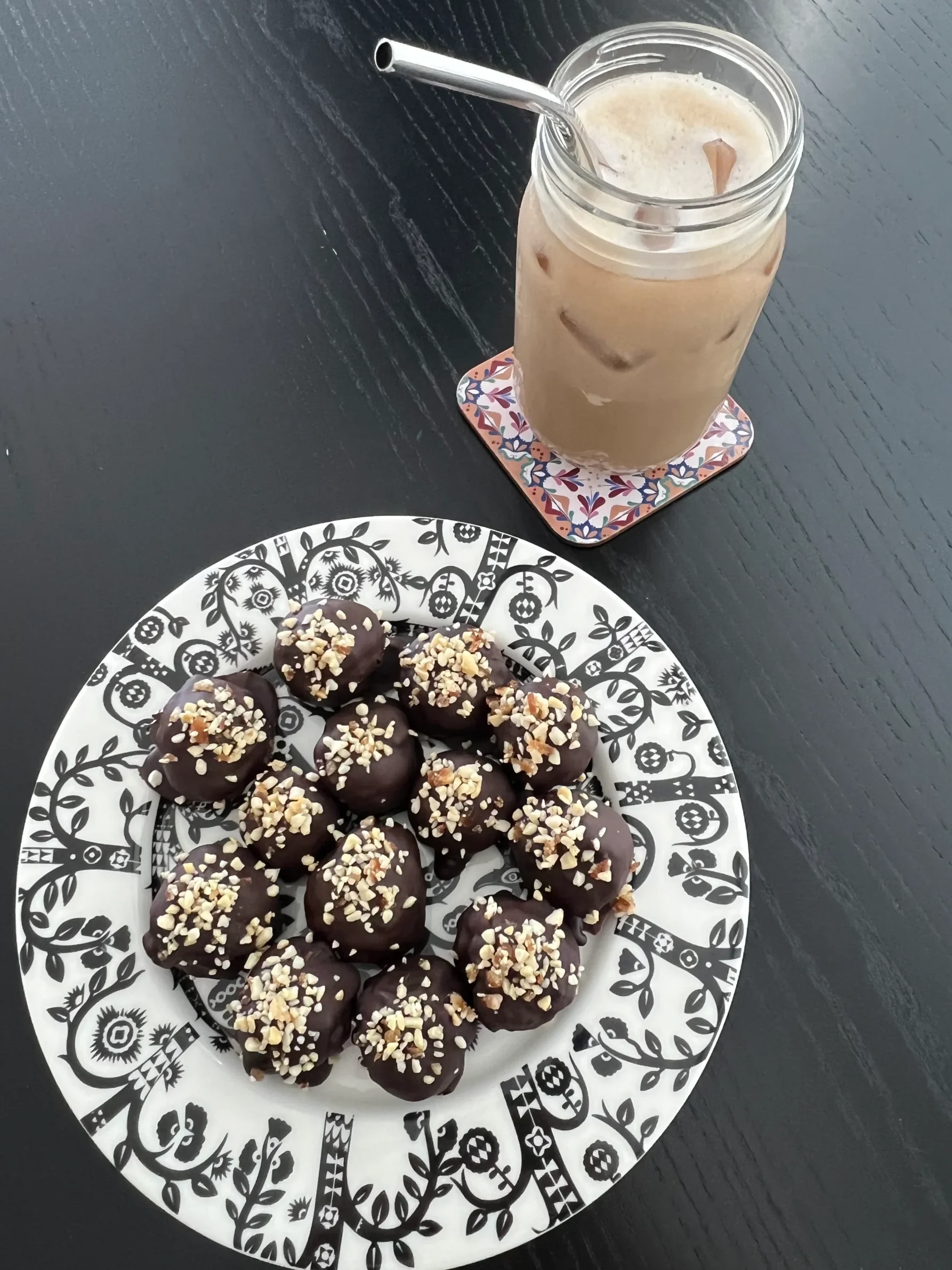 Chocolate-coated date and cashew energy balls and a glass of iced coffee.